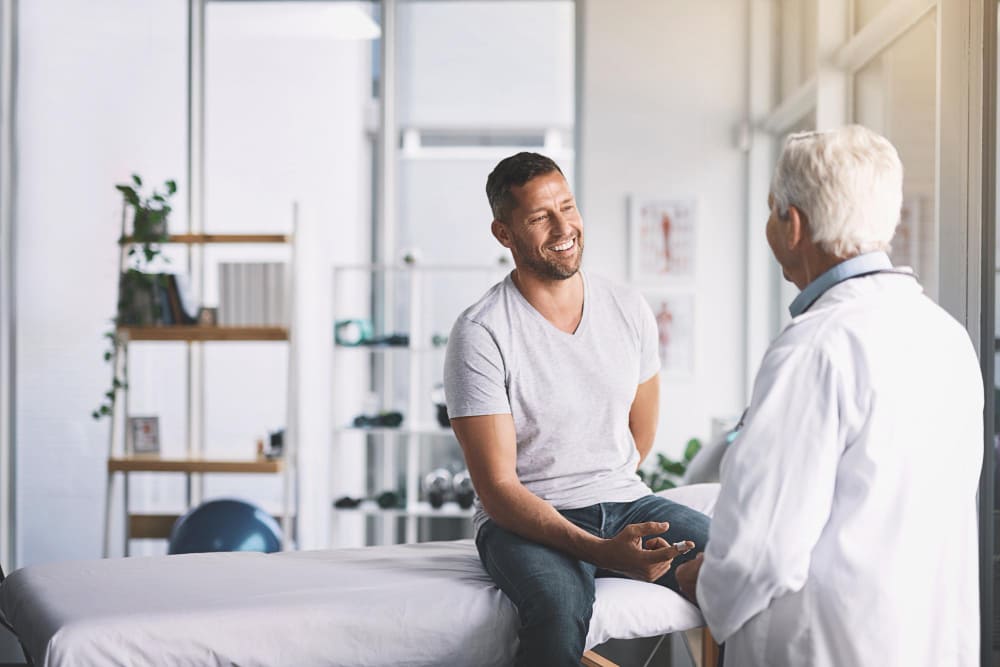 Doctor man and patient on bed for healthcare with insulin plaster for diabetes injection or treatment mature professional health insurance or glucose check with blood pressure or wellness checkup