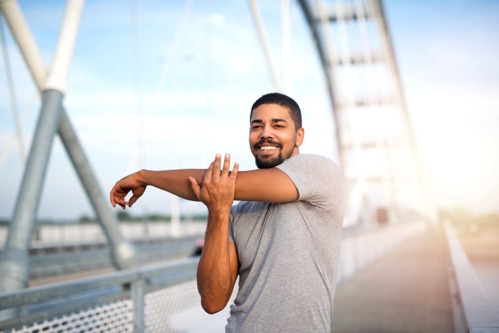 
Attractive smiling sportsman warming up his body for an outdoor training